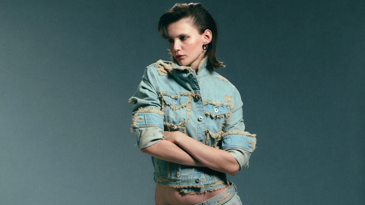 Cheap Monday reflecting model wearing edgy denim in an alternative fashion style.